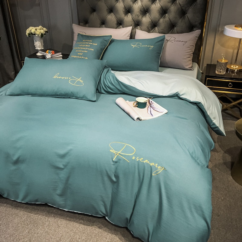 Ensfarvet Sengesæt Med Blå Og Grøn Broderet Skrift